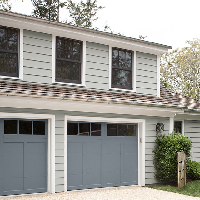 Rich gray-painted garage doors are a nice balanced contrast to this home’s off-white painted siding with blue-gray undertones and white trim. Rich gray-painted garage doors are a nice balanced contrast to this home’s off-white painted siding with blue-gray undertones and white trim.
