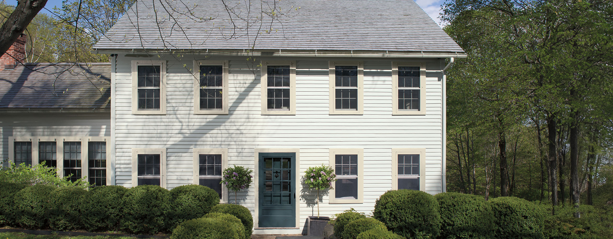 Residential exterior featuring Colonial saltbox with shrub-lined front walk. Residential exterior featuring Colonial saltbox with shrub-lined front walk.