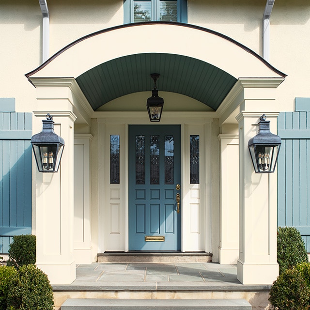 A beautiful white-painted house with a light-blue front door, trim and shutters, and a covered arched entryway with columns and lanterns. A beautiful white-painted house with a light-blue front door, trim and shutters, and a covered arched entryway with columns and lanterns.