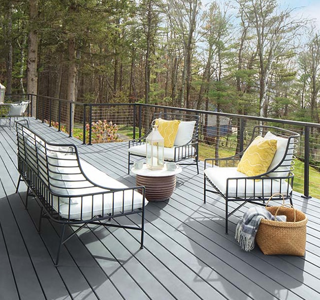 Pretty white cushioned outdoor furniture with yellow pillows on a spacious light gray stained deck. Pretty white cushioned outdoor furniture with yellow pillows on a spacious light gray stained deck.