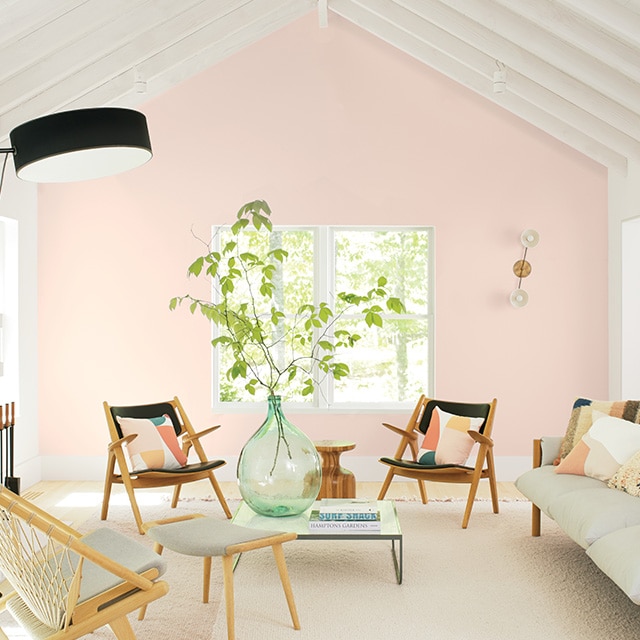 A soft pink-painted accent wall is the highlight of this inviting white painted living room with a vaulted beamed ceiling, fireplace and casual white and black furnishings. A soft pink-painted accent wall is the highlight of this inviting white painted living room with a vaulted beamed ceiling, fireplace and casual white and black furnishings.