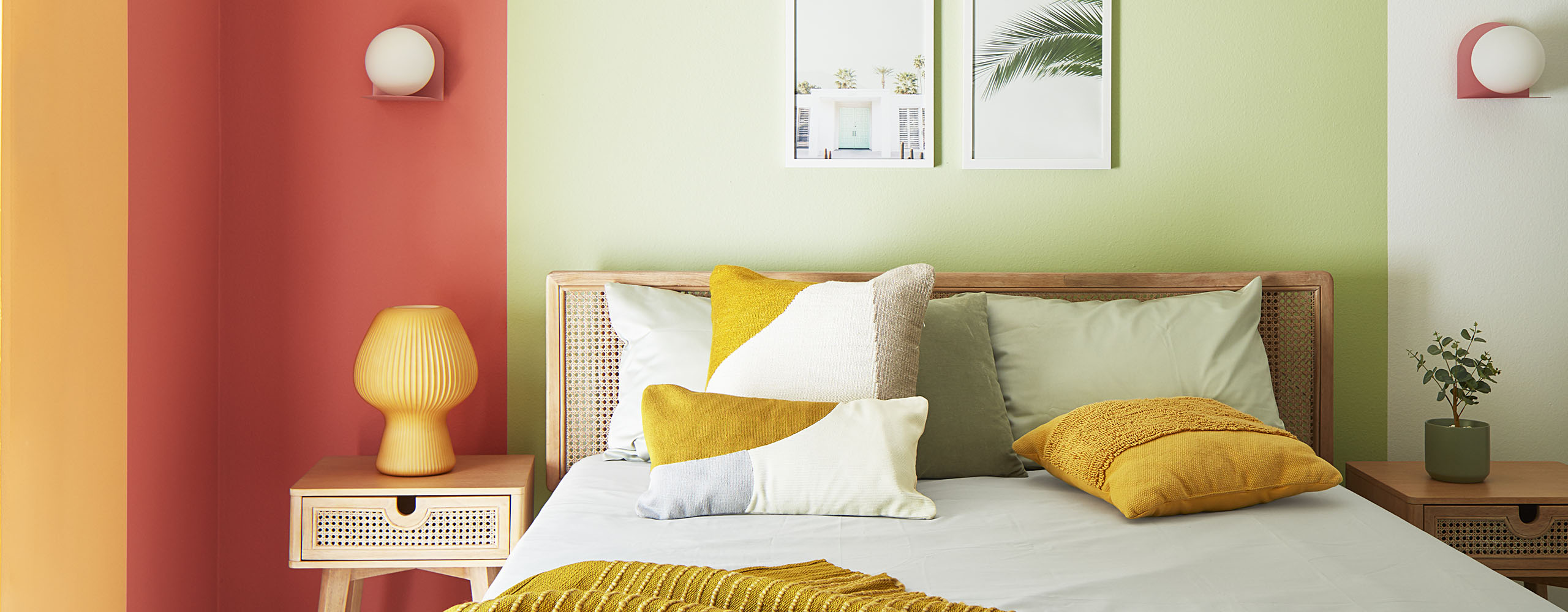 A cheerful corner bedroom space with golden yellow, orange, and green painted overlapping rectangles on a white wall behind a modern bed and night stands. A cheerful corner bedroom space with golden yellow, orange, and green painted overlapping rectangles on a white wall behind a modern bed and night stands.