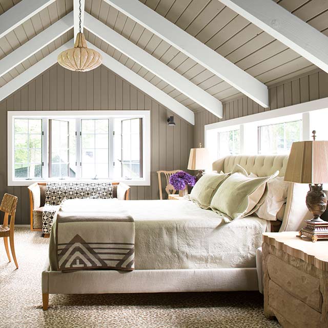 A master bedroom with gray-painted walls and vaulted ceiling, white wood beams and trim, and neutral colored décor. A master bedroom with gray-painted walls and vaulted ceiling, white wood beams and trim, and neutral colored décor.