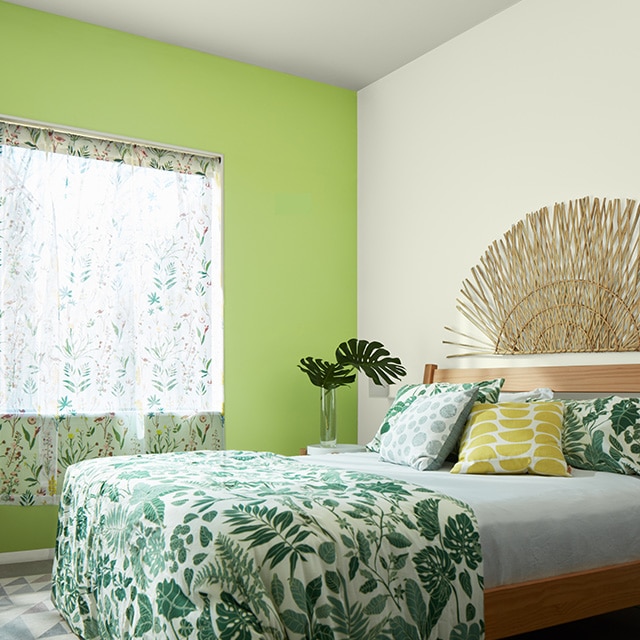 A green-painted accent wall makes a fun statement in this bedroom with white walls, tropical print bedding and curtains, and a wicker art piece over the headboard. A green-painted accent wall makes a fun statement in this bedroom with white walls, tropical print bedding and curtains, and a wicker art piece over the headboard.