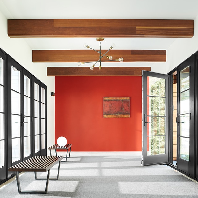 A white-painted hallway with a red accent wall, wood beam ceiling, black-trim windows and door, and modern furnishings. A white-painted hallway with a red accent wall, wood beam ceiling, black-trim windows and door, and modern furnishings.