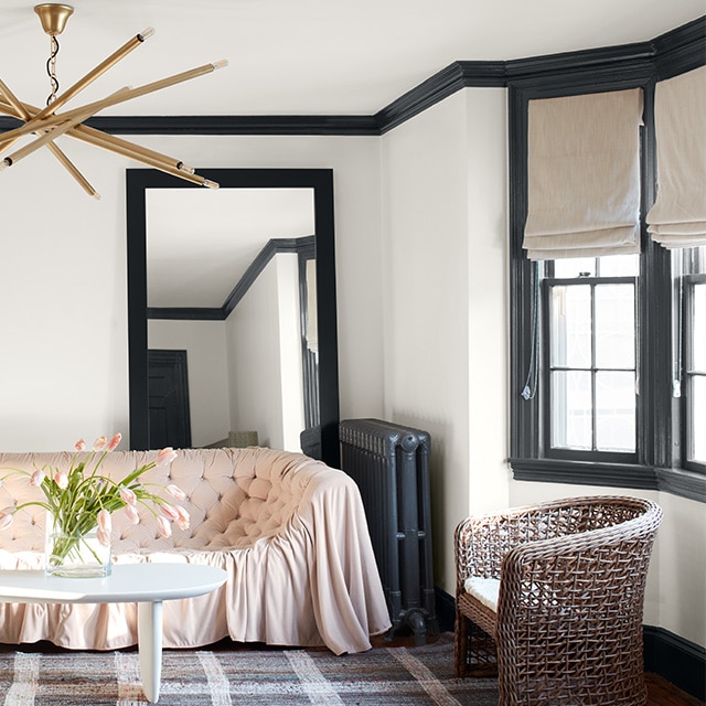 Dark gray-painted trim and radiator contrast nicely against white walls in this eclectic style living room with a pink sofa and modern chandelier. Dark gray-painted trim and radiator contrast nicely against white walls in this eclectic style living room with a pink sofa and modern chandelier.
