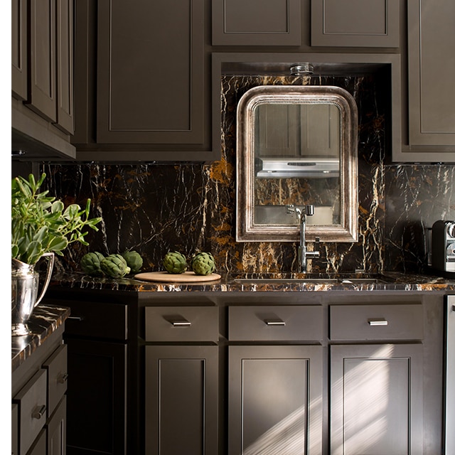 Rich, brown-painted kitchen cabinets, a brown marble backsplash and an ornate mirror create a sumptuous culinary setting. Rich, brown-painted kitchen cabinets, a brown marble backsplash and an ornate mirror create a sumptuous culinary setting.
