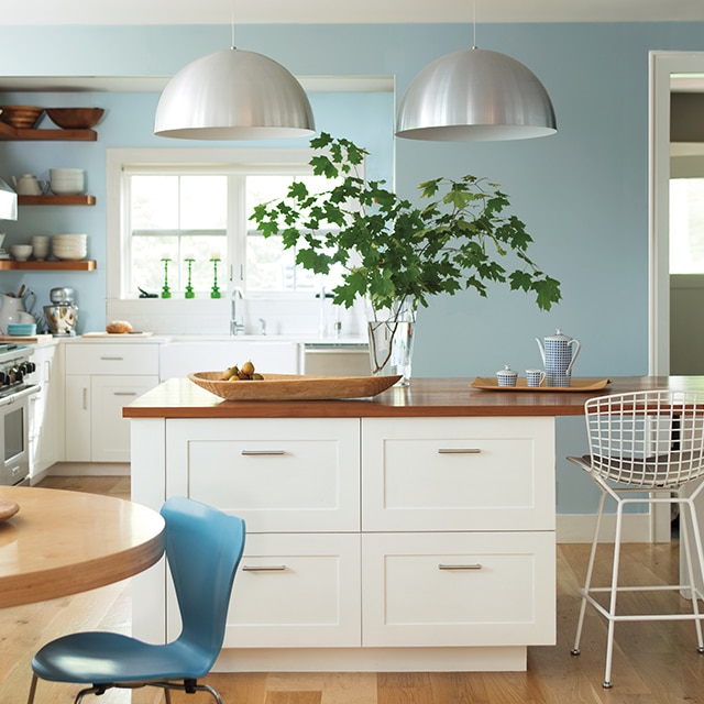 A bright and airy contemporary kitchen with white-painted cabinets and center island with a wood top, and light blue walls. A bright and airy contemporary kitchen with white-painted cabinets and center island with a wood top, and light blue walls.