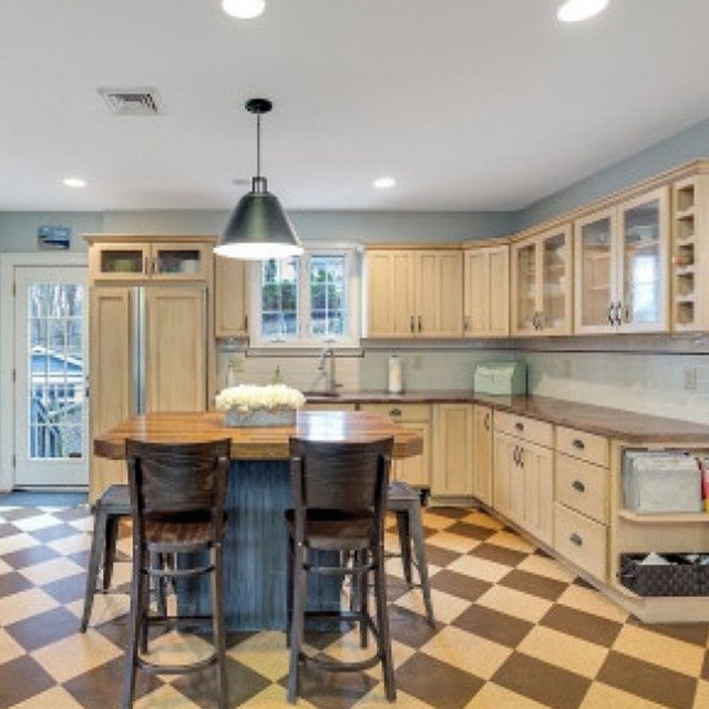 A kitchen with off-white painted cabinets, light-blue walls, a center wood island, and a checkboard floor before a makeover. A kitchen with off-white painted cabinets, light-blue walls, a center wood island, and a checkboard floor before a makeover.