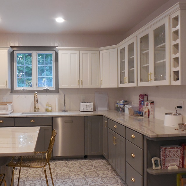 The same kitchen after a makeover, with white-painted upper cabinets, dark gray lower cabinets and island, white countertops and white walls. The same kitchen after a makeover, with white-painted upper cabinets, dark gray lower cabinets and island, white countertops and white walls.