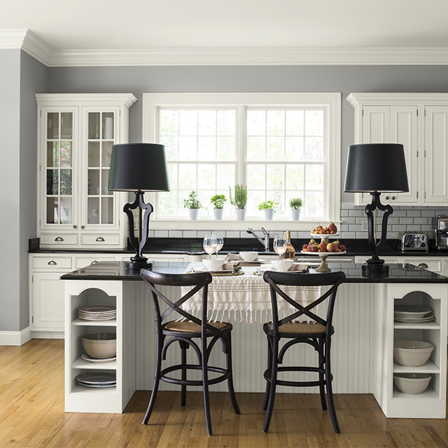 This light gray-painted kitchen keeps it fresh with white cabinetry and subway tile backsplash, adding a dash of depth with black countertops. This light gray-painted kitchen keeps it fresh with white cabinetry and subway tile backsplash, adding a dash of depth with black countertops.