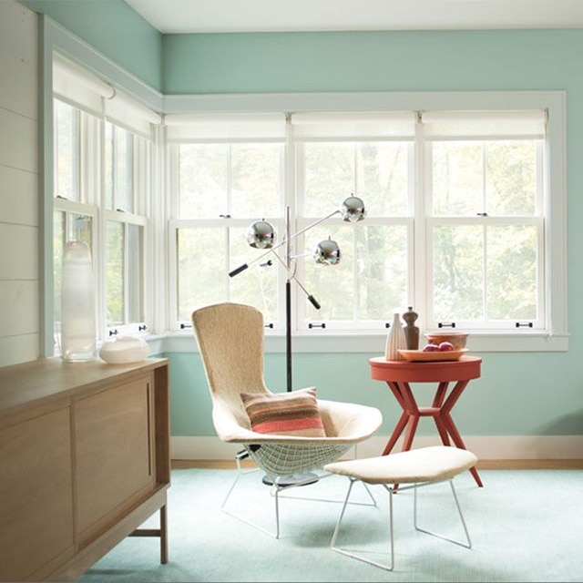 A pretty light blue-green painted living room corner with light gray trim, multiple windows, and contemporary furniture. A pretty light blue-green painted living room corner with light gray trim, multiple windows, and contemporary furniture.