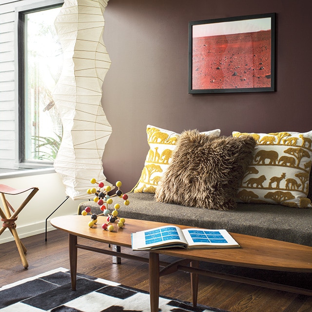 An eclectic living room with a brown-painted wall behind a sofa, a white side wall, and animal print décor. An eclectic living room with a brown-painted wall behind a sofa, a white side wall, and animal print décor.