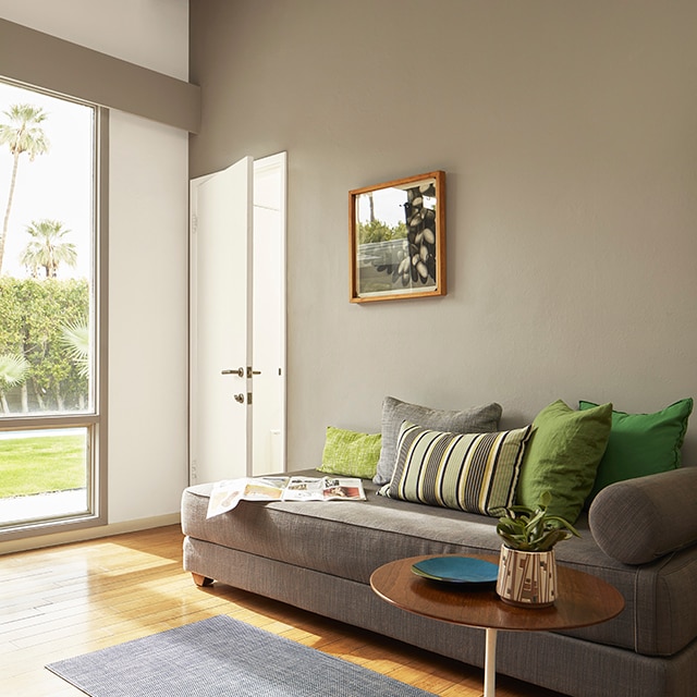 A sunlit living room with a taupe-painted accent wall, white wood beamed vaulted ceiling, a white door and modern style furnishings. A sunlit living room with a taupe-painted accent wall, white wood beamed vaulted ceiling, a white door and modern style furnishings.