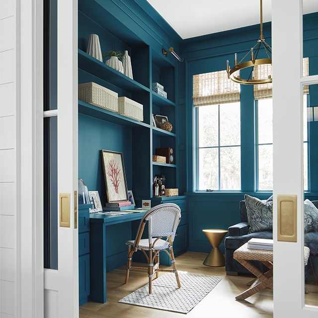 A beautiful teal-painted home office with built-in shelves, cabinets and desk, tall windows, beach décor, and open white pocket doors with brass hardware. A beautiful teal-painted home office with built-in shelves, cabinets and desk, tall windows, beach décor, and open white pocket doors with brass hardware.