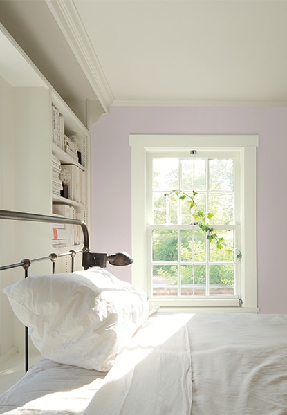 Large bedroom with light pink walls, white built-in shelves, and a metal bedframe with white sheets. Large bedroom with light pink walls, white built-in shelves, and a metal bedframe with white sheets.