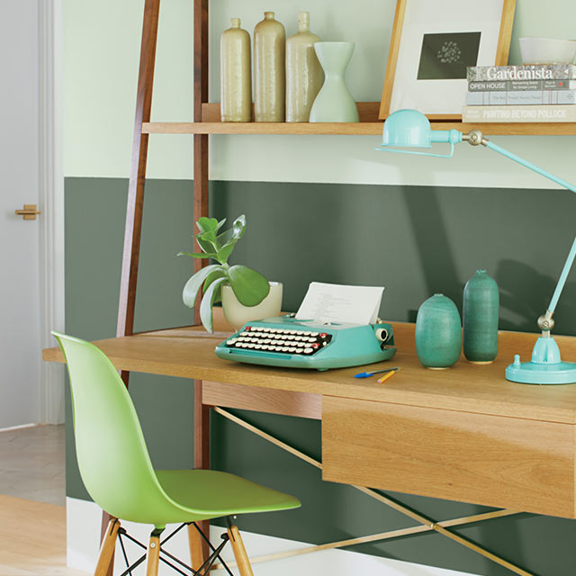 An office with a two-tone green painted wall, a white door, a modern desk with shelves and colored vases, and a green chair. An office with a two-tone green painted wall, a white door, a modern desk with shelves and colored vases, and a green chair.