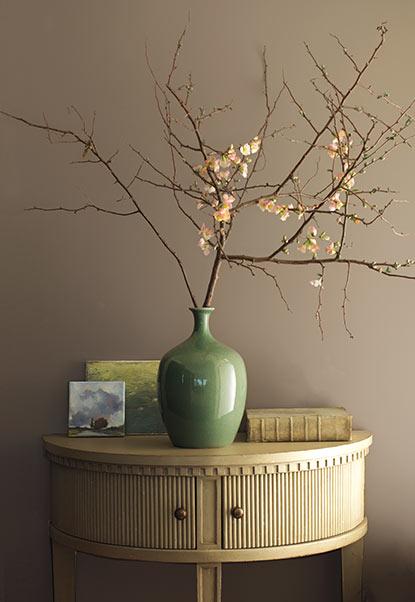 Minimalist floral arrangement in green vase against gray-brown wall. Minimalist floral arrangement in green vase against gray-brown wall.