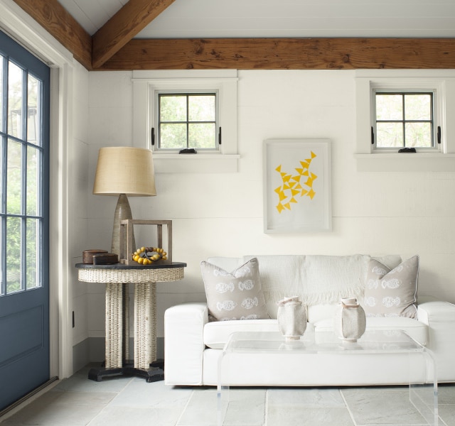 Gray-painted doors provide a warm welcome into this white-painted seating area with white couch and modern furniture. Gray-painted doors provide a warm welcome into this white-painted seating area with white couch and modern furniture.
