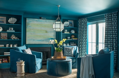 An all-blue painted living room with blue club chairs and built in shelving. An all-blue painted living room with blue club chairs and built in shelving.