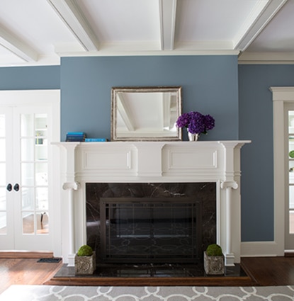 A white fireplace and mantel in a blue living room with windowed double doors. A white fireplace and mantel in a blue living room with windowed double doors.
