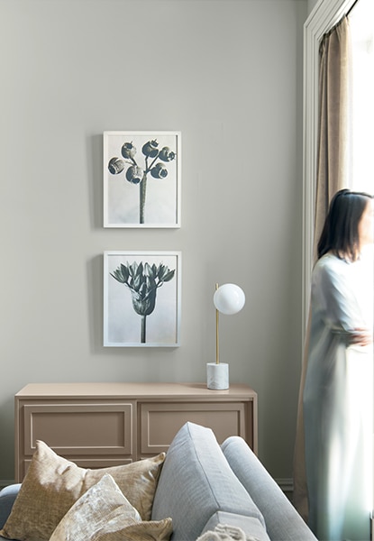 Light gray living room with two picture frames hanging above a wood cabinet next to a gray sofa. Light gray living room with two picture frames hanging above a wood cabinet next to a gray sofa.