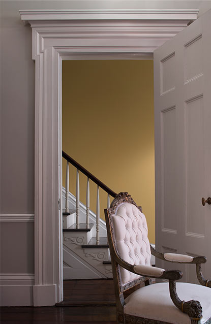 A living room in light gray features a door opening to a yellow-painted foyer. A living room in light gray features a door opening to a yellow-painted foyer.