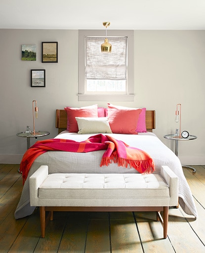 A neutral colored bedroom with walls painted in Natural Cream OC-14, bold red throw pillows, and blanket. A neutral colored bedroom with walls painted in Natural Cream OC-14, bold red throw pillows, and blanket.