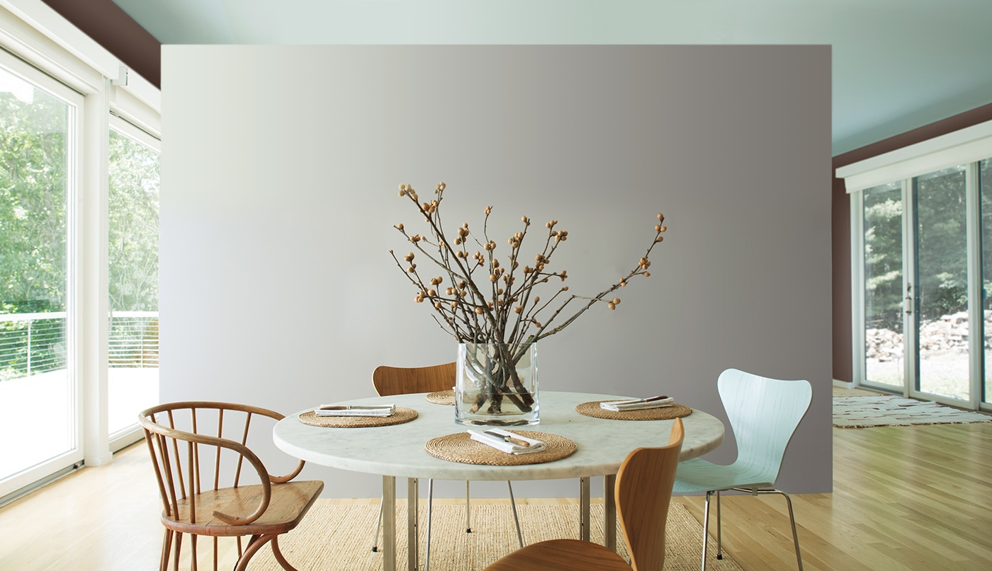Airy kitchen with gray accent wall and mint ceiling; large paper lantern lighting above circular table with wooden chairs.