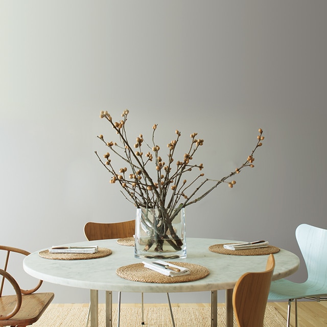 Airy kitchen with gray accent wall and mint ceiling; large paper lantern lighting above circular table with wooden chairs.