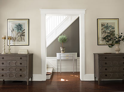 A gray and neutral hallway leads to a white staircase. A gray and neutral hallway leads to a white staircase.