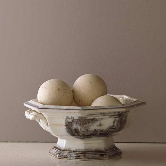 A decorative rustic bowl against a painted wall in Smoked Oyster 2109-40.