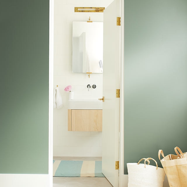 A dark green wall leads to a bright, neutral bathroom