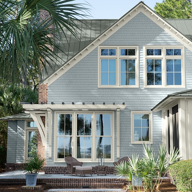Pretty light-gray painted house with white trim, shaded by palm trees. Pretty light-gray painted house with white trim, shaded by palm trees.