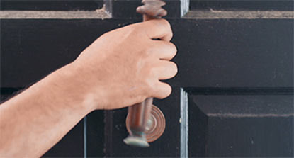 A person removing hardware from an exterior door in preparation for painting. A person removing hardware from an exterior door in preparation for painting.