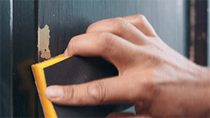A person sanding a door. A person sanding a door.