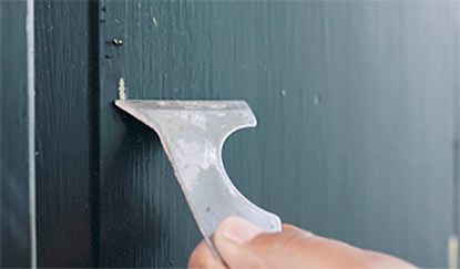 A person scraping loose paint from a door. A person scraping loose paint from a door.