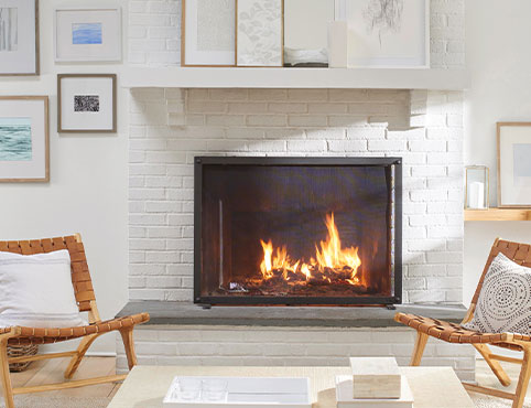 A white painted brick fireplace flanked by matching wooden chairs. A white painted brick fireplace flanked by matching wooden chairs.