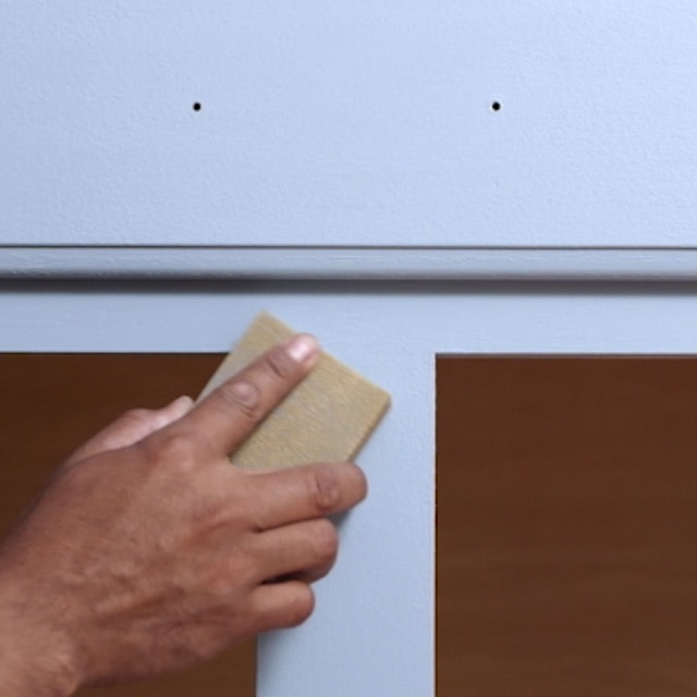 A person sanding a kitchen cabinet face frame between recoats. A person sanding a kitchen cabinet face frame between recoats.
