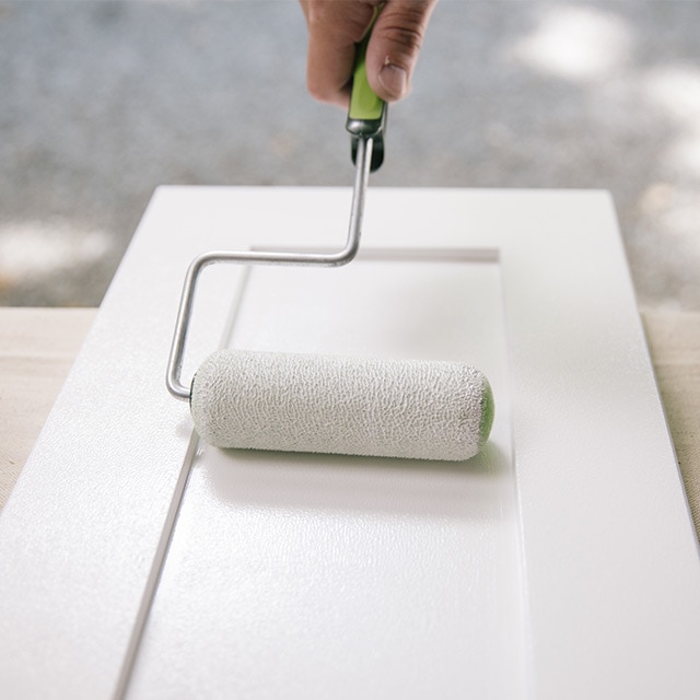 Applying primer to the bathroom vanity cabinet with a roller. Applying primer to the bathroom vanity cabinet with a roller.