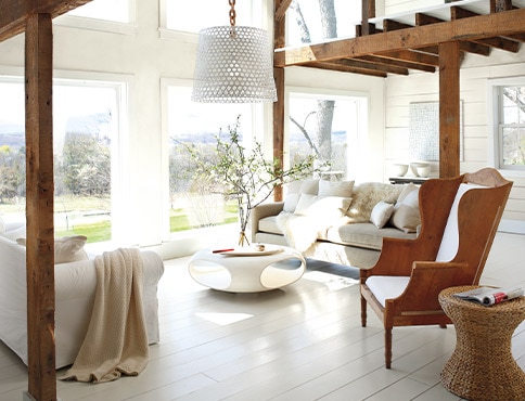 A living room with white-painted walls and floor, wooden armchair, cozy sofas, and a modern coffee table. A living room with white-painted walls and floor, wooden armchair, cozy sofas, and a modern coffee table.