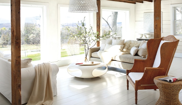 A living room with white-painted walls and floor, wooden armchair, cozy sofas, and a modern coffee table. A living room with white-painted walls and floor, wooden armchair, cozy sofas, and a modern coffee table.