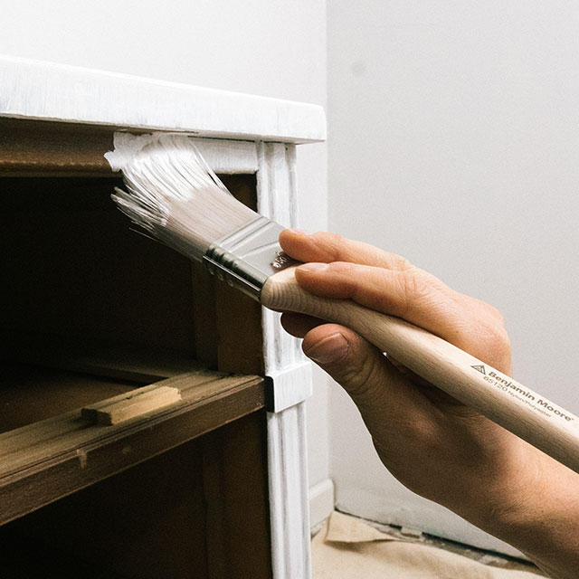 Applying primer to the surface of a cabinet in a room with white walls. Applying primer to the surface of a cabinet in a room with white walls.