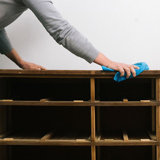 Cleaning surface of a dresser cabinet with a wet rag. Cleaning surface of a dresser cabinet with a wet rag.