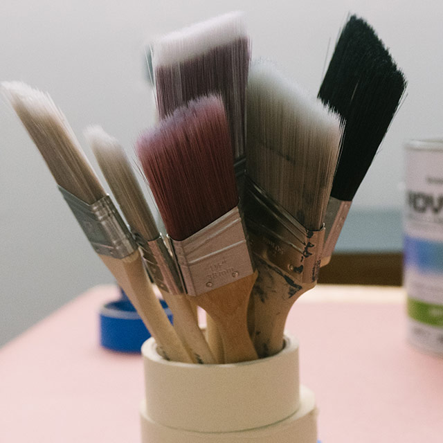 A variety of different paintbrushes clustered together inside stacked rolls of tape. A variety of different paintbrushes clustered together inside stacked rolls of tape.