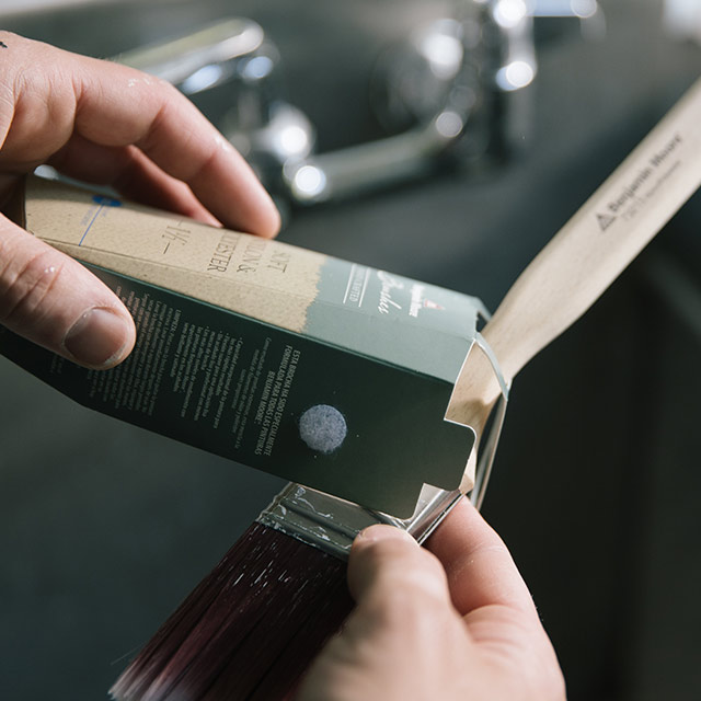 A person places a paintbrush back into its original packaging to maintain bristle shape. A person places a paintbrush back into its original packaging to maintain bristle shape.