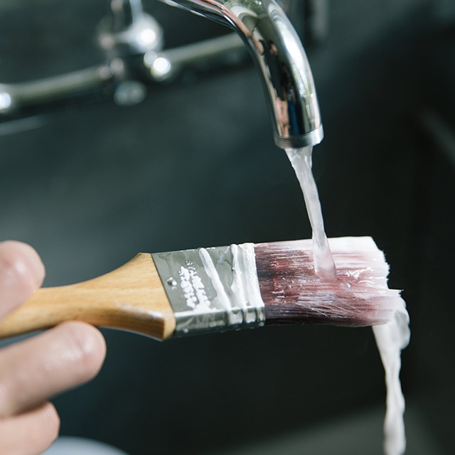 Rinsing paintbrush under running water. Rinsing paintbrush under running water.
