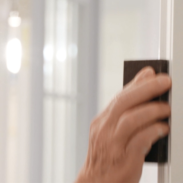 A person sanding white painted trim. A person sanding white painted trim.