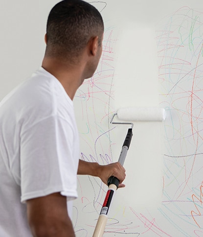 A painting contractor rolling Fresh Start® primer over crayon scribbles on a white wall. A painting contractor rolling Fresh Start® primer over crayon scribbles on a white wall.