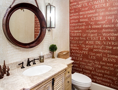 A beautiful bathroom with a bold red accent wall with the Cajun dictionary stenciled on top.